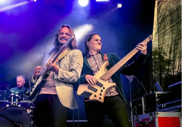 Två personer spelar gitarr lutar sig mot varandra